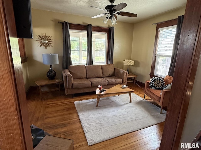 living room with healthy amount of natural light, ceiling fan, wood finished floors, a textured ceiling, and baseboards
