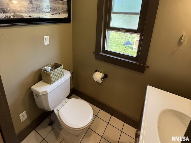 half bathroom featuring toilet, baseboards, and tile patterned floors