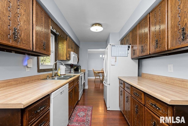 kitchen with white appliances, a sink, dark wood-type flooring, and light countertops