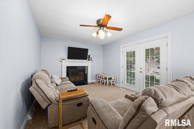 living area with french doors, carpet flooring, baseboards, a ceiling fan, and a fireplace with flush hearth