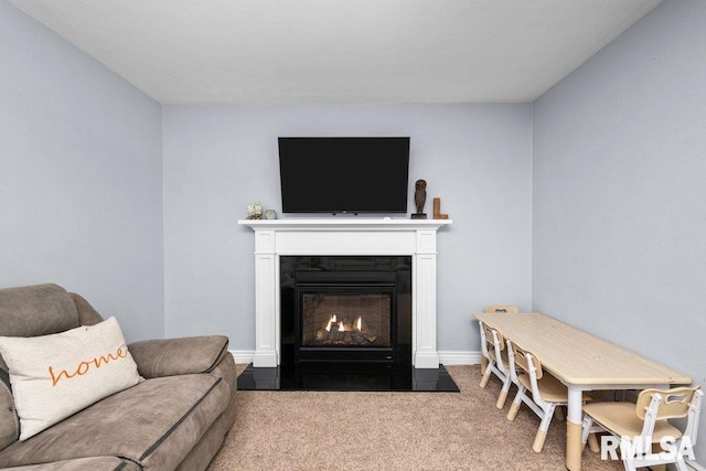 carpeted living room featuring a fireplace with flush hearth and baseboards