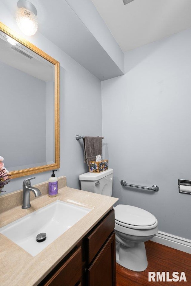 bathroom featuring toilet, wood finished floors, vanity, and baseboards