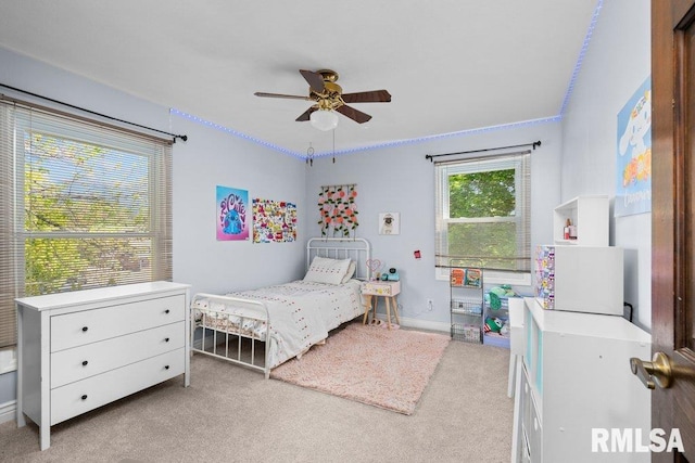 bedroom featuring light colored carpet, baseboards, and a ceiling fan