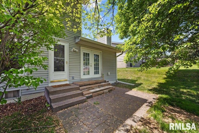 entrance to property with french doors, a chimney, and a yard