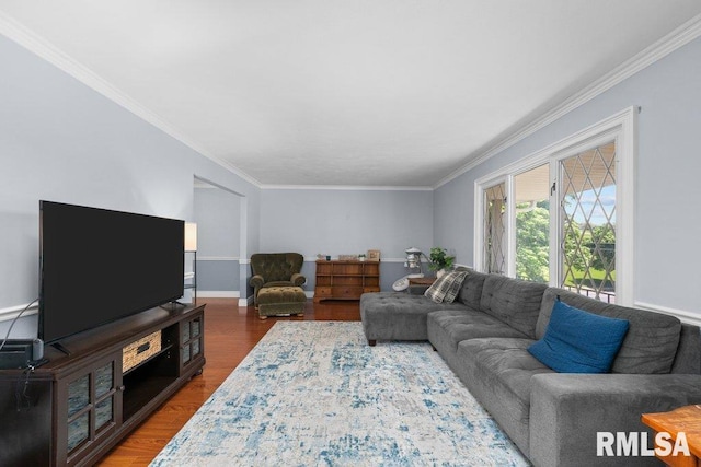 living room featuring wood finished floors, ornamental molding, and baseboards