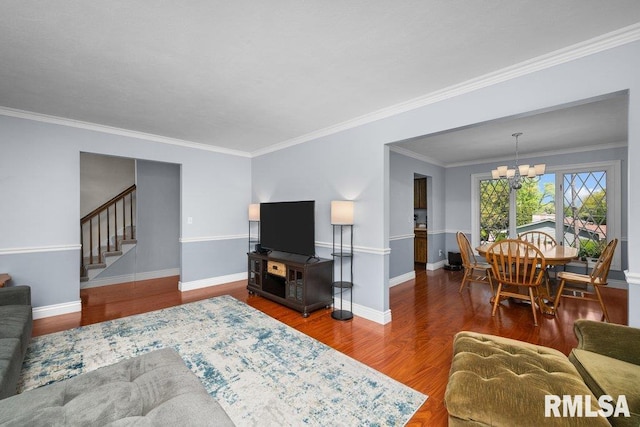 living room with a chandelier, stairway, wood finished floors, ornamental molding, and baseboards