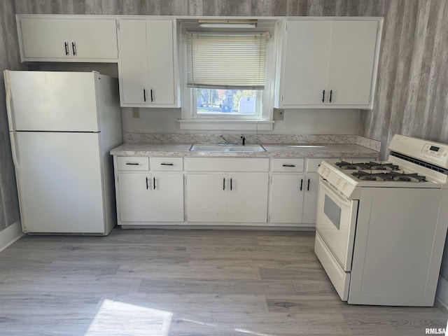 kitchen featuring white appliances, a sink, light countertops, and white cabinetry