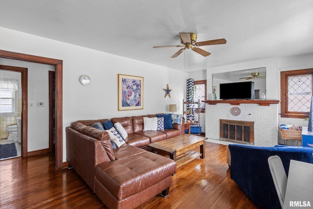 living room featuring a ceiling fan, wood finished floors, a fireplace, and baseboards