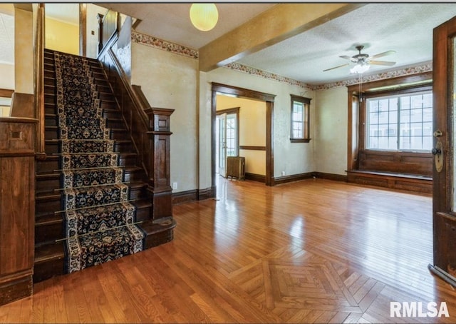 stairway with baseboards, ceiling fan, and parquet floors