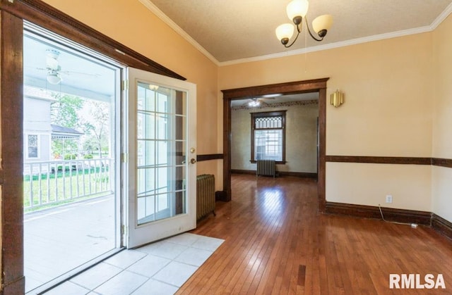 entryway featuring radiator heating unit, hardwood / wood-style flooring, ornamental molding, baseboards, and a chandelier