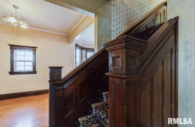 staircase featuring wood finished floors, ornamental molding, and baseboards