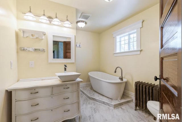 full bathroom featuring radiator heating unit, marble finish flooring, a freestanding tub, vanity, and toilet