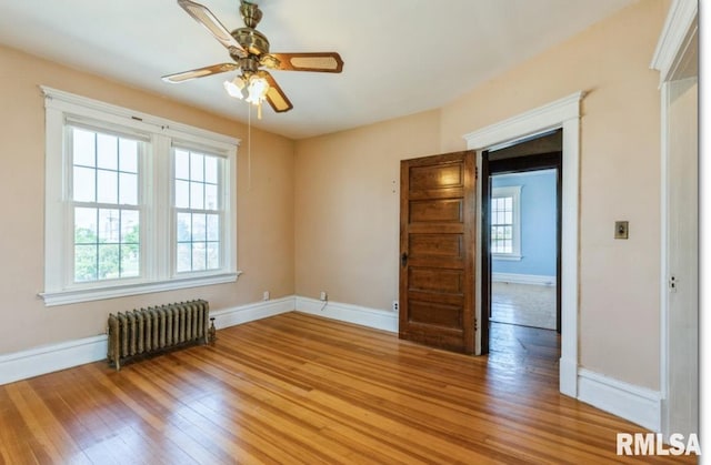 spare room with radiator, baseboards, and light wood finished floors