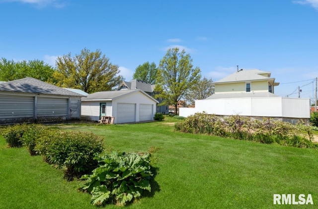view of grassy yard with a garage and an outbuilding