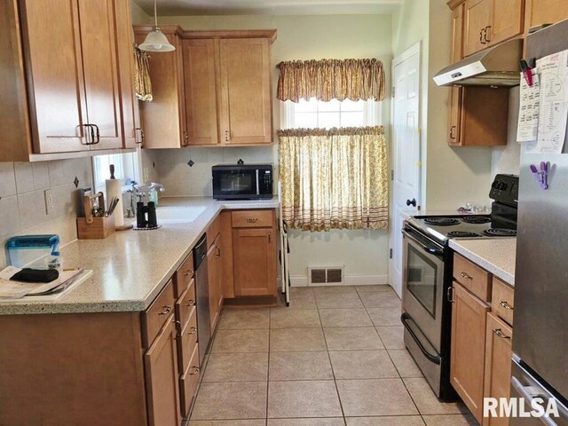 kitchen featuring stainless steel appliances, under cabinet range hood, light countertops, and healthy amount of natural light