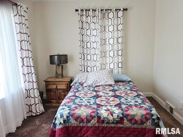 bedroom featuring dark carpet and baseboards