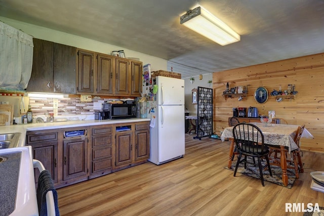 kitchen with freestanding refrigerator, black microwave, range, light countertops, and light wood-type flooring