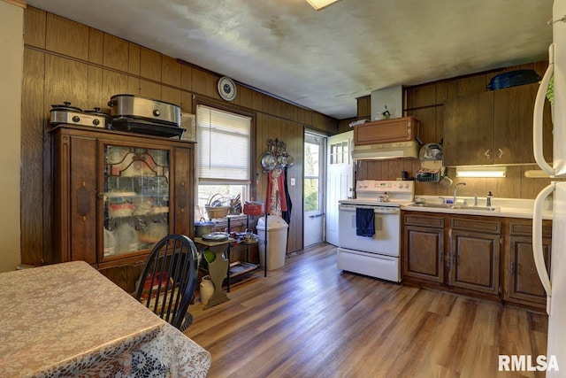 kitchen featuring electric stove, a sink, wood finished floors, range hood, and light countertops