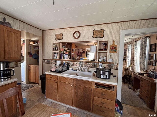 451 S Grove St, Kewanee, IL 61443 - kitchen featuring a sink, wallpapered walls, light countertops, brown cabinetry, and crown molding