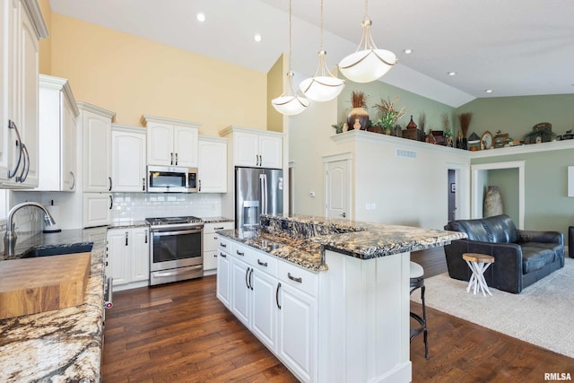 24711 178th St, Pleasant Valley, IA 52767 - kitchen with appliances with stainless steel finishes, a sink, high vaulted ceiling, a kitchen bar, and dark stone counters