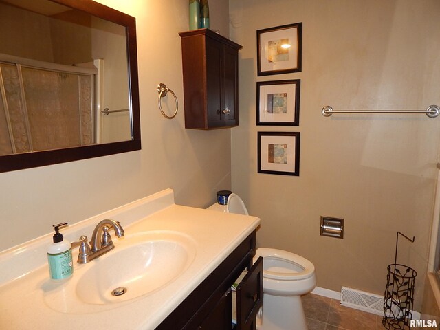 bathroom with an enclosed shower, toilet, tile patterned flooring, vanity, and baseboards