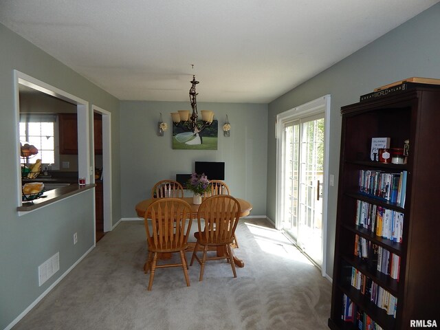 dining room featuring a chandelier, healthy amount of natural light, and carpet