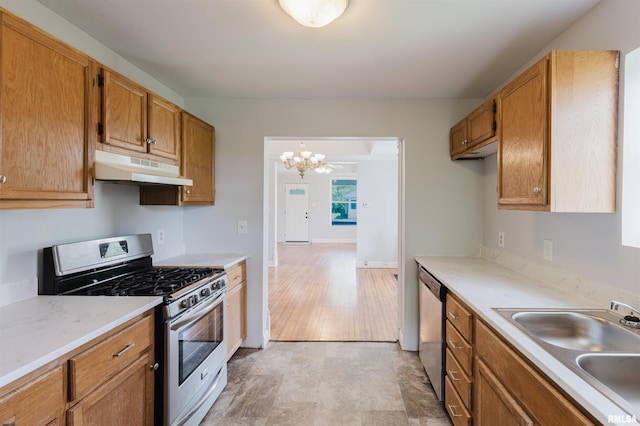 kitchen with under cabinet range hood, stainless steel appliances, a sink, a chandelier, and light countertops