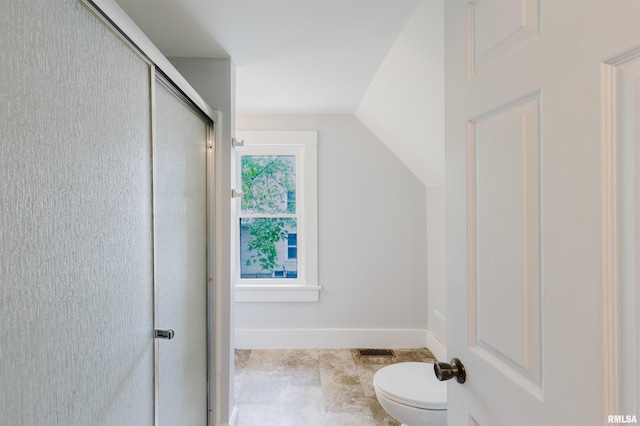 full bathroom with toilet, a shower with door, tile patterned flooring, and vaulted ceiling