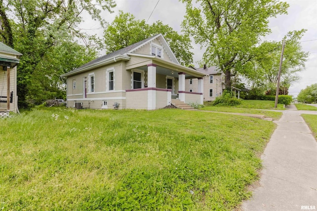 view of front of property with a front yard, covered porch, central AC, and a shingled roof