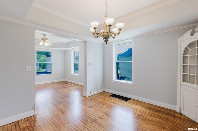 unfurnished dining area with a chandelier, light wood-type flooring, baseboards, ornamental molding, and a tray ceiling