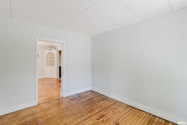 empty room with a paneled ceiling, baseboards, and light wood finished floors