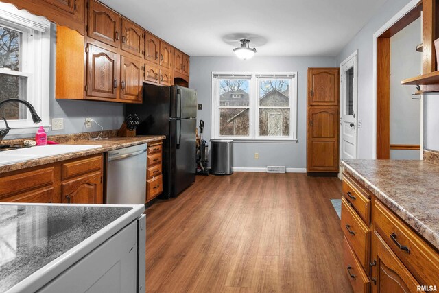2307 N Ripley St, Davenport, IA 52803 - kitchen featuring stainless steel dishwasher, a sink, dark wood-style floors, brown cabinets, and freestanding refrigerator