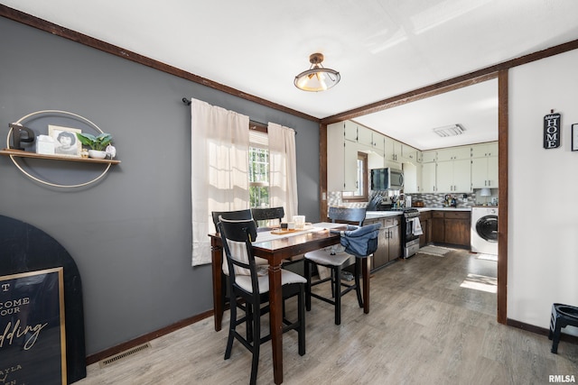 dining room with washer / dryer, light wood-style floors, and baseboards