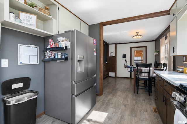 kitchen featuring stainless steel fridge with ice dispenser, white cabinetry, light wood-style flooring, gas range, and light countertops