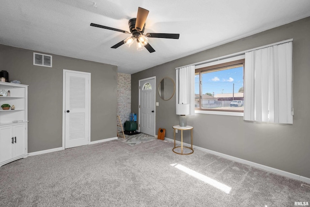 carpeted foyer entrance featuring a ceiling fan and baseboards