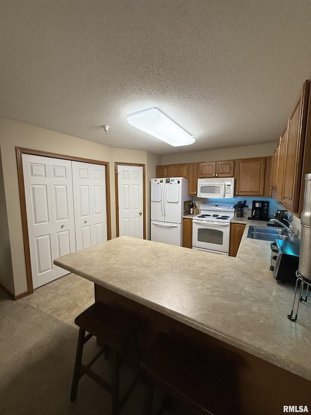 3205 S 16th Ave Unit 203, Eldridge, IA 52748 - kitchen featuring white appliances, a sink, a peninsula, brown cabinets, and light countertops