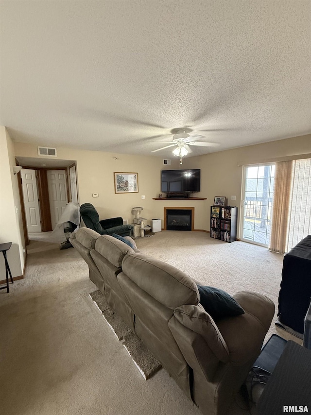 3205 S 16th Ave Unit 203, Eldridge, IA 52748 - living room with light carpet, a ceiling fan, a fireplace, and a textured ceiling