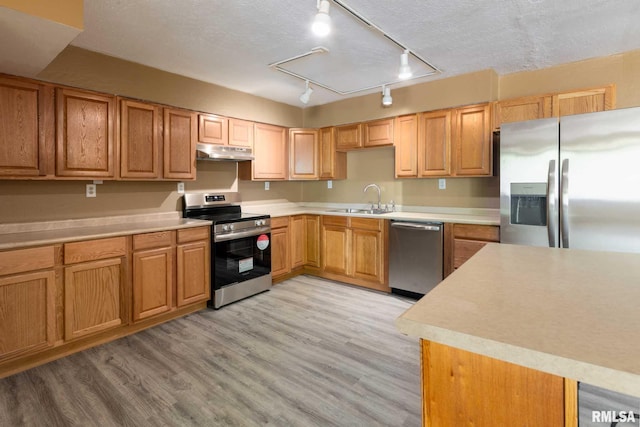 1401 Thomas St, Carterville, IL 62918 - kitchen with appliances with stainless steel finishes, under cabinet range hood, a sink, light wood finished floors, and light countertops