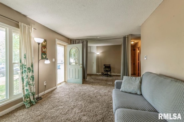 carpeted living area featuring a textured ceiling and baseboards