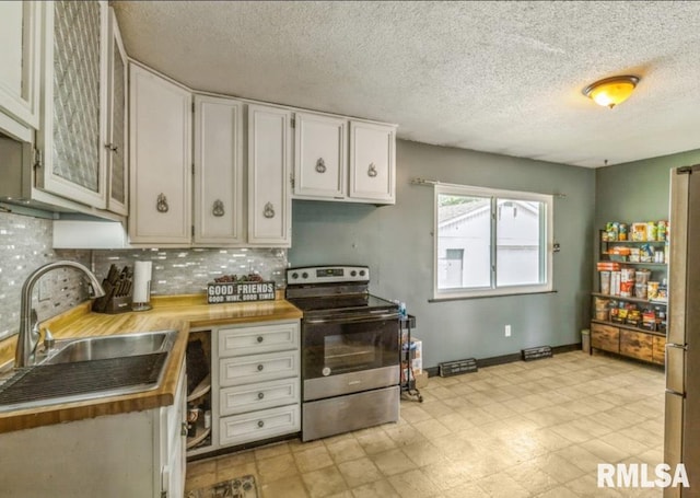 kitchen with stainless steel electric stove, a sink, tasteful backsplash, white cabinets, and a textured ceiling