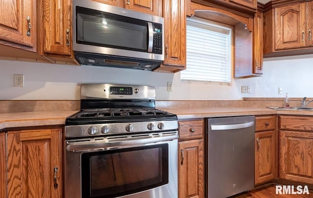 2505 Joel Dr, Herrin, IL 62948 - kitchen featuring stainless steel appliances, brown cabinets, a sink, light countertops, and wood finished floors