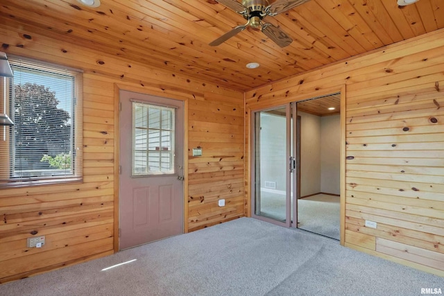 unfurnished room featuring carpet floors, a ceiling fan, wood walls, and wooden ceiling