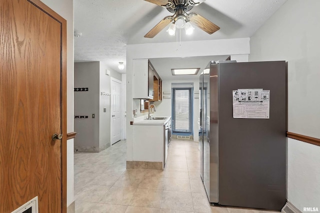 kitchen with freestanding refrigerator, ceiling fan, a sink, light countertops, and light tile patterned floors