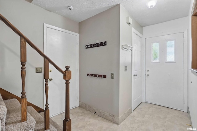 entrance foyer with stairs, light tile patterned floors, and a textured ceiling