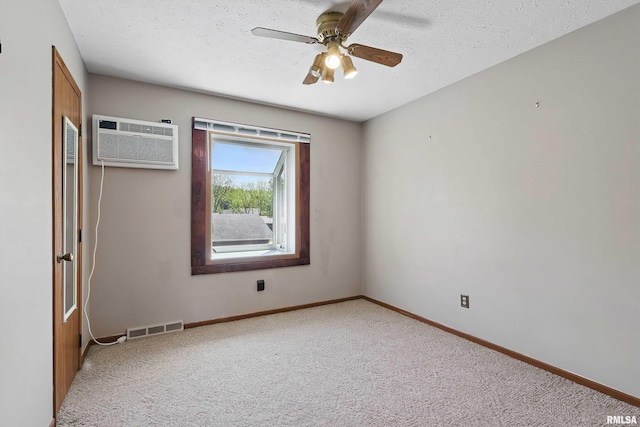 carpeted empty room featuring a wall unit AC, baseboards, ceiling fan, and a textured ceiling