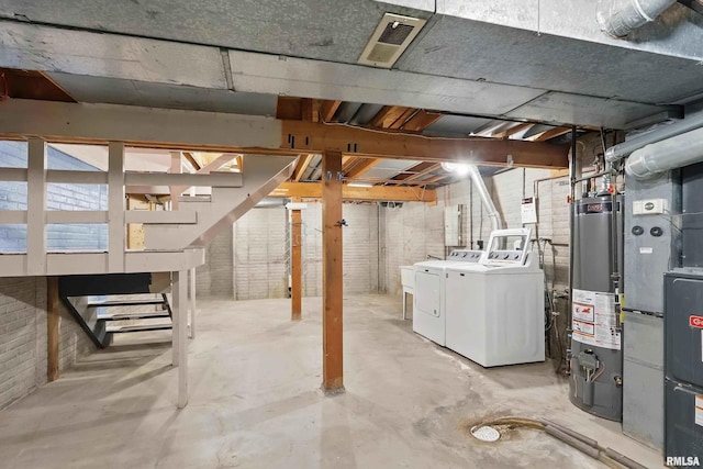 unfinished basement featuring washing machine and clothes dryer, gas water heater, and stairs