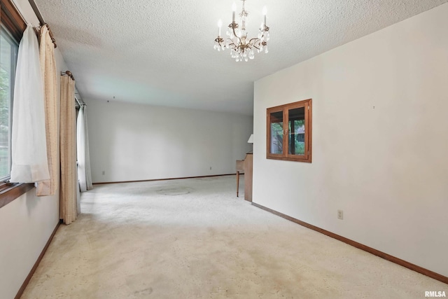 3816 Woodland Ct, Davenport, IA 52807 - carpeted empty room featuring a chandelier, baseboards, a textured ceiling, and plenty of natural light