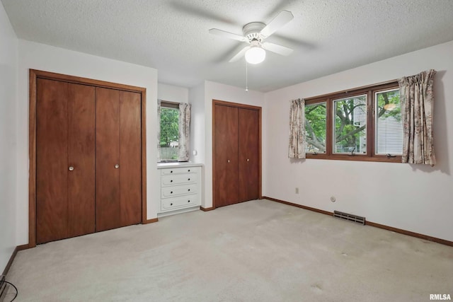 3816 Woodland Ct, Davenport, IA 52807 - unfurnished bedroom featuring two closets, multiple windows, baseboards, light carpet, and a textured ceiling