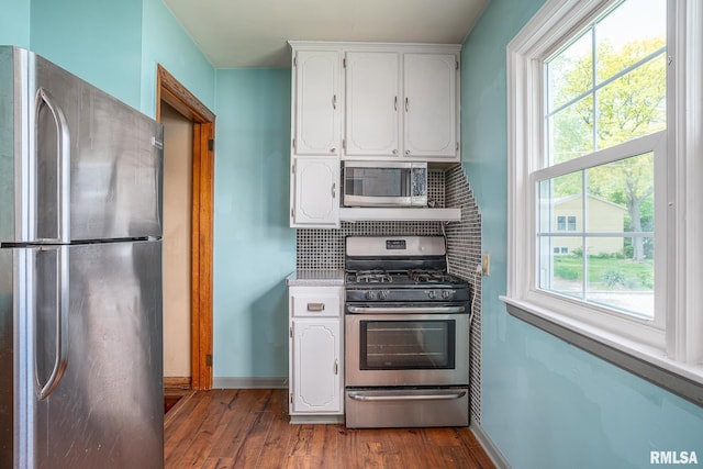 kitchen featuring appliances with stainless steel finishes, white cabinetry, dark wood-style floors, backsplash, and baseboards
