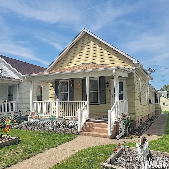 shotgun-style home with a porch and a front lawn